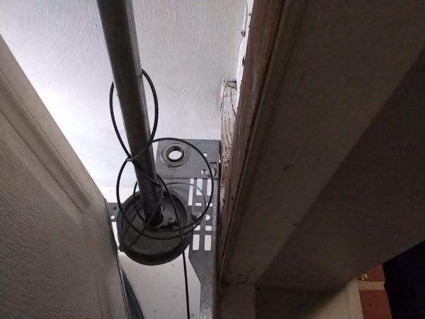Lift cable unwound from the cable drum and hanging loose around the torsion shaft of a garage door