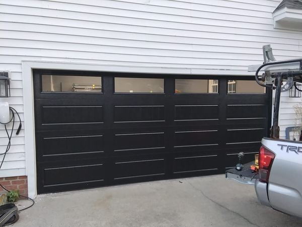 Garage door installation in Virginia Beach: black 16x7 steel-back carriage-house door with long panels and a row of windows in southern Virginia Beach, ZIP 23457