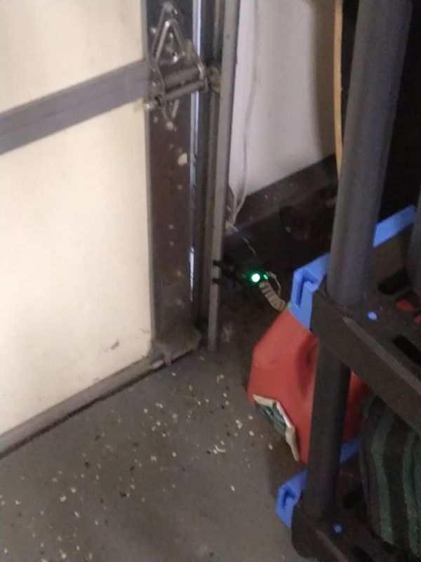 Garage door opener installation in Virginia Beach: safety photo eye with a solid green light mounted low on the door track after a Kempsville opener replacement