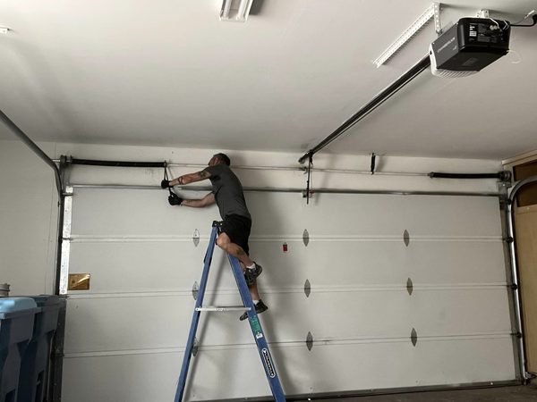 Seaside tech inspecting a broken torsion spring before quoting a written line-item replacement